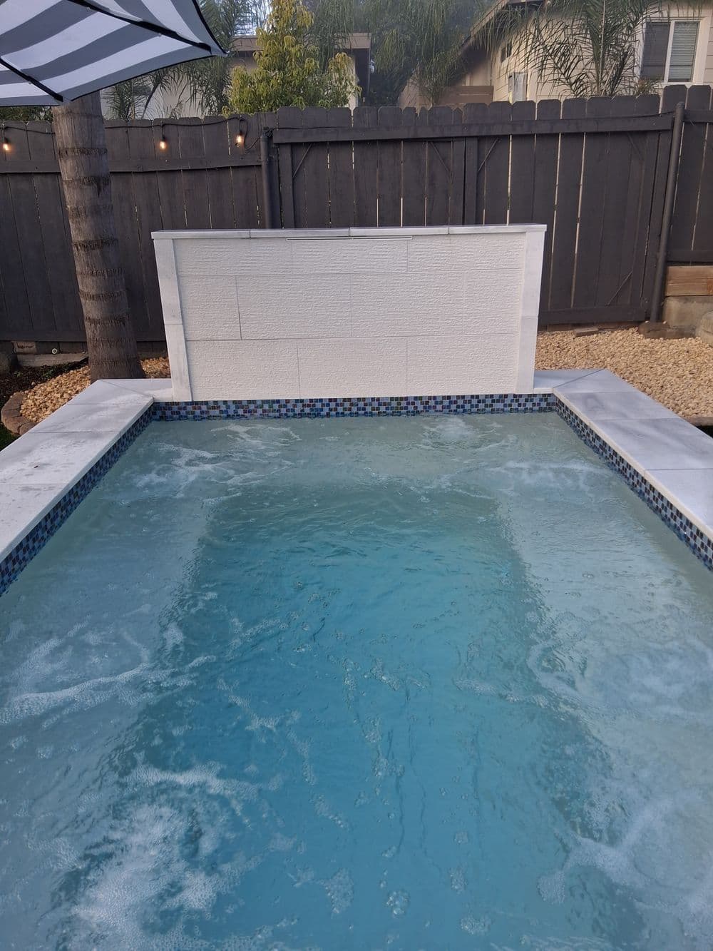 Relaxing backyard hot tub with bubbling water and a privacy wall surrounded by landscaping.