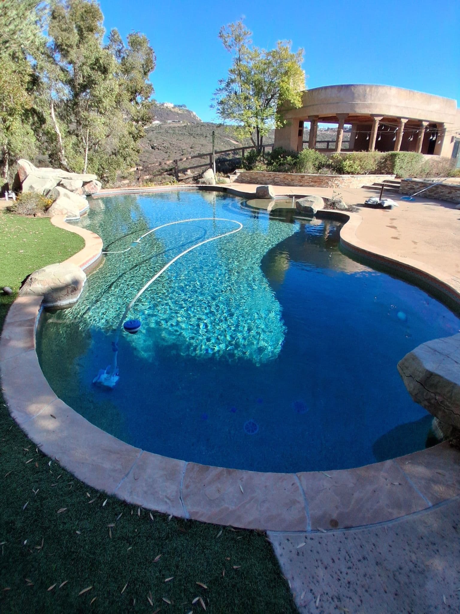 luxurious outdoor swimming pool surrounded by lush greenery and scenic hills in sunlight
